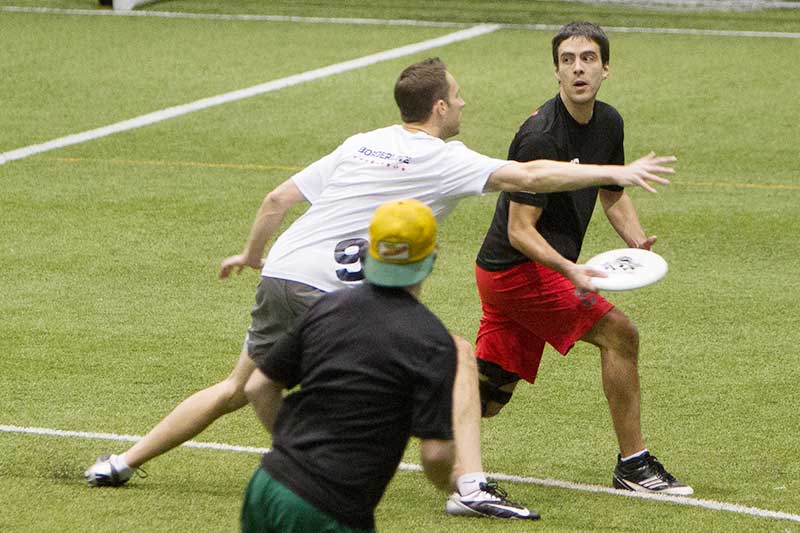 A player with a disc looks to throw to his team mate while being actively marked